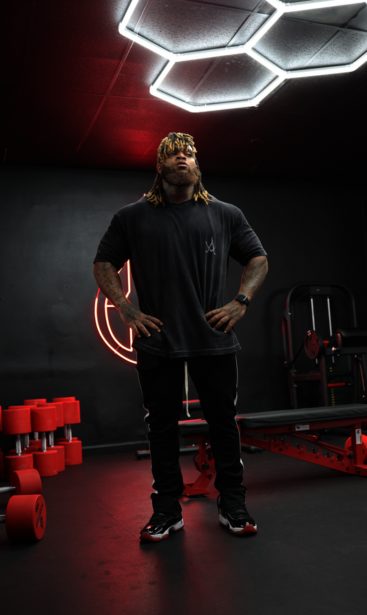 man wearing black sustainable fashion outfit standing in modern gym with hexagonal lights and red accents