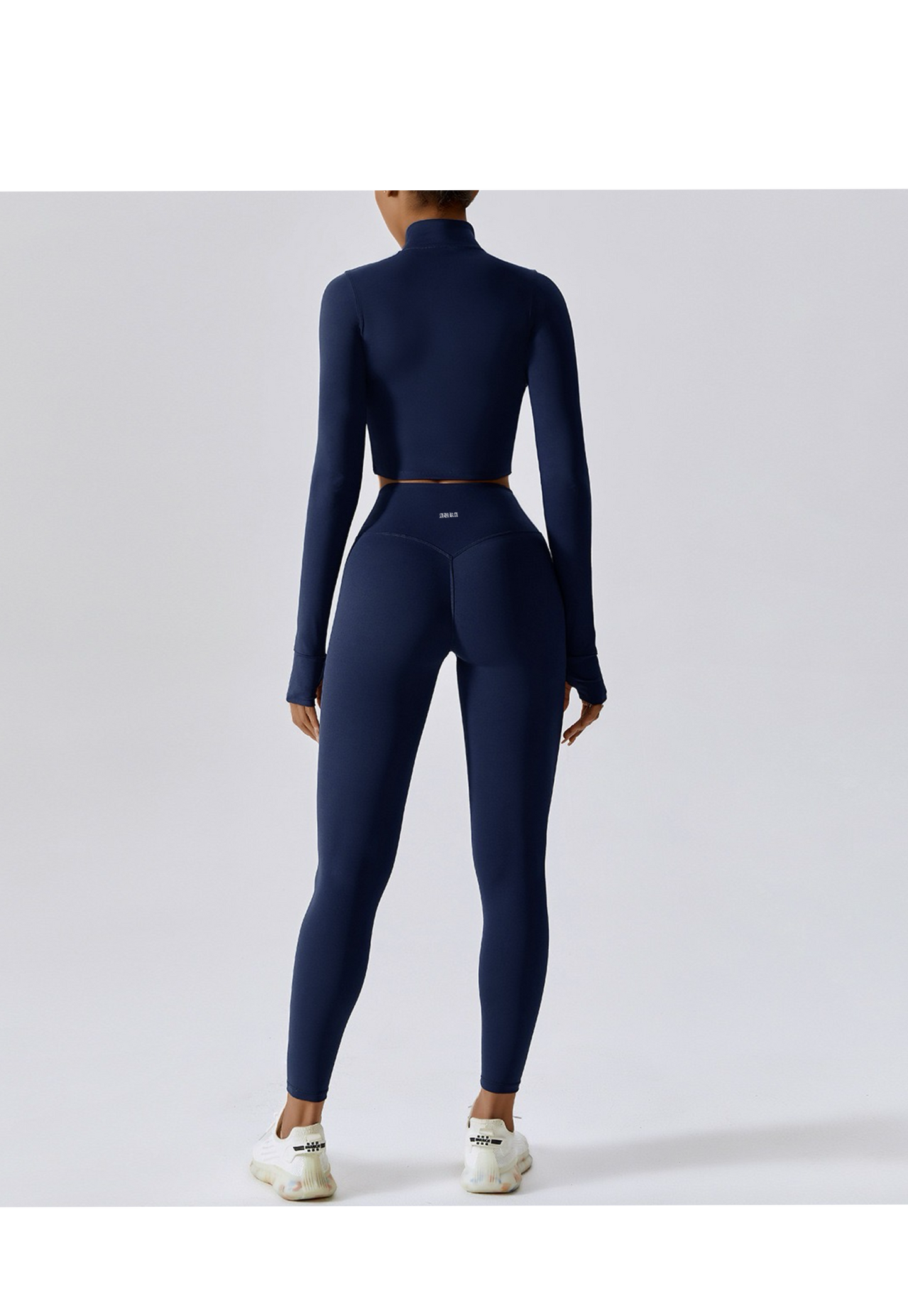 Woman wearing high-waist navy gym leggings and crop top from back view